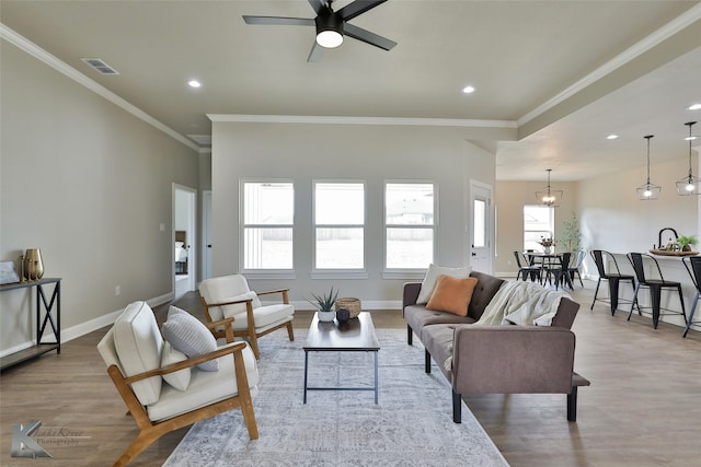 living room with light hardwood / wood-style flooring, ceiling fan, and ornamental molding