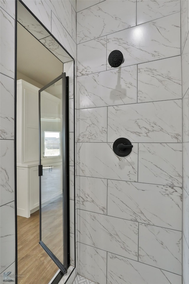 bathroom featuring hardwood / wood-style flooring and a tile shower