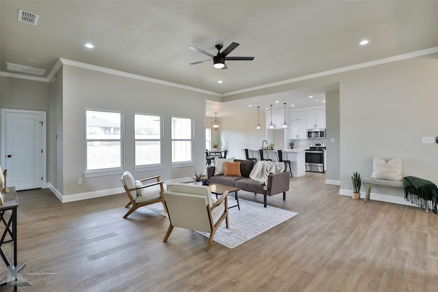 living room with ceiling fan, crown molding, and light hardwood / wood-style flooring