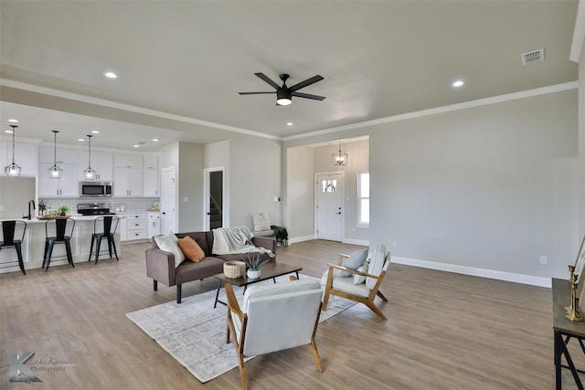 living room featuring crown molding, light hardwood / wood-style flooring, and ceiling fan