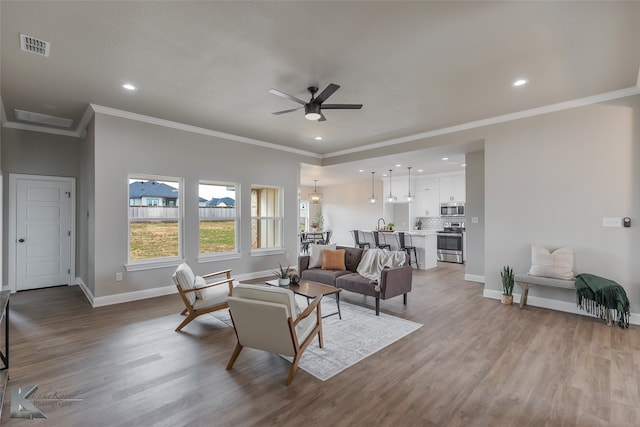 living room with ceiling fan, light hardwood / wood-style floors, and ornamental molding