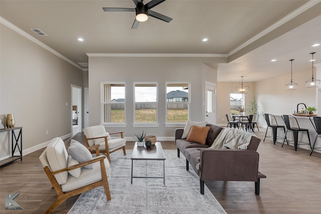 living room with light hardwood / wood-style flooring, ceiling fan, and ornamental molding