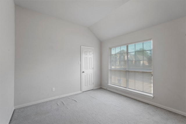 carpeted spare room featuring lofted ceiling