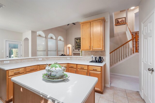 kitchen with light tile patterned floors, tasteful backsplash, kitchen peninsula, and a center island