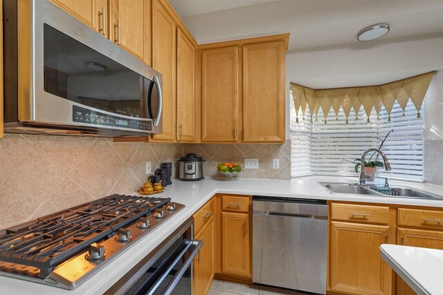 kitchen with appliances with stainless steel finishes, tasteful backsplash, sink, and light tile patterned flooring