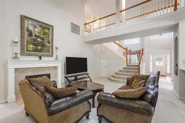 carpeted living room with a fireplace and a towering ceiling