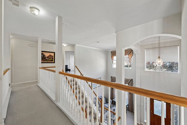 corridor featuring light colored carpet, a chandelier, and ornamental molding