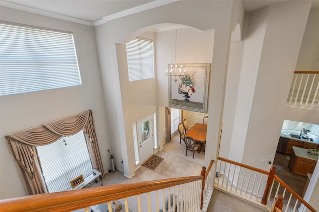 tiled entrance foyer featuring a wealth of natural light, an inviting chandelier, and crown molding