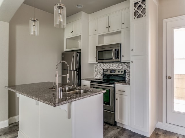 kitchen featuring an island with sink, hanging light fixtures, stainless steel appliances, a kitchen bar, and white cabinets