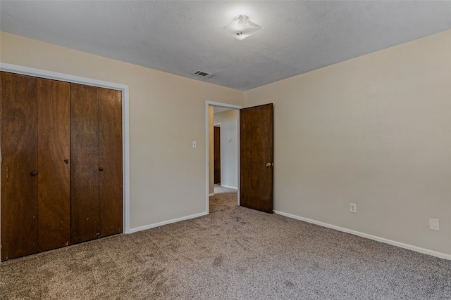 unfurnished bedroom with a textured ceiling, a closet, and light carpet