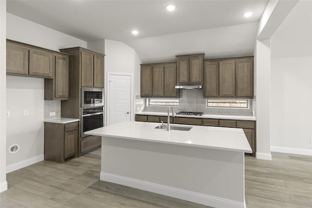 kitchen featuring lofted ceiling, backsplash, sink, an island with sink, and stainless steel appliances