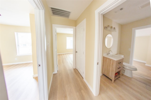 corridor with light wood-type flooring and sink