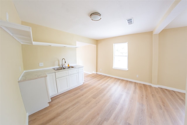 interior space with light hardwood / wood-style flooring, sink, and white cabinets