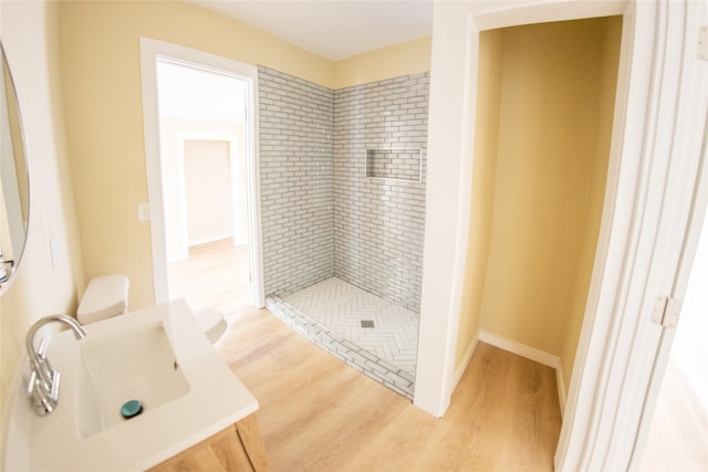 bathroom featuring hardwood / wood-style floors, tiled shower, and sink