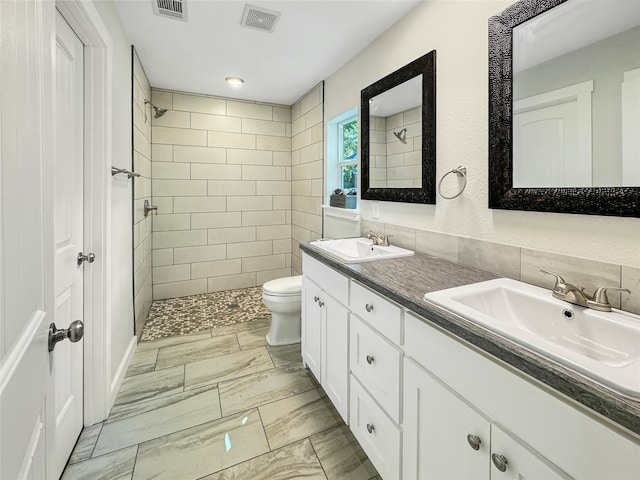 bathroom featuring toilet, vanity, and tiled shower