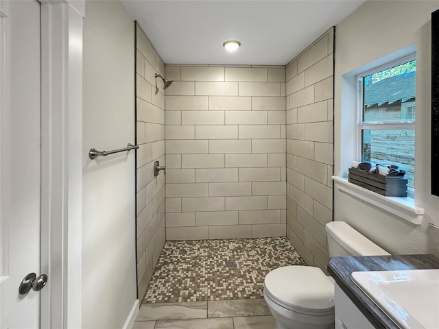 bathroom with vanity, toilet, and tiled shower