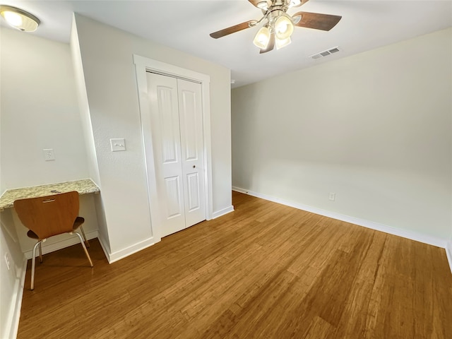 unfurnished bedroom with a closet, wood-type flooring, and ceiling fan