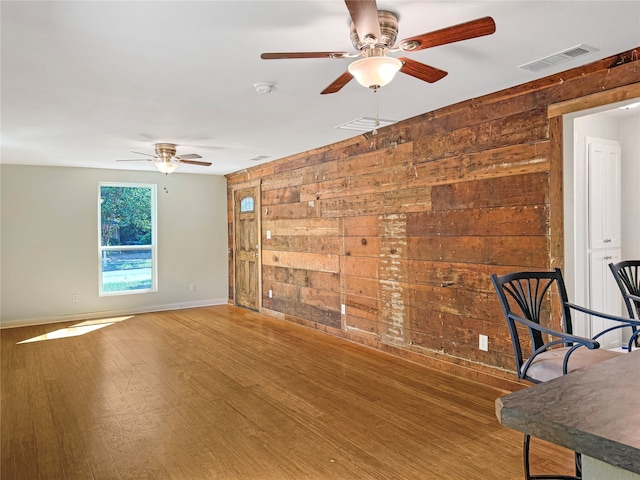 interior space featuring wooden walls, ceiling fan, and hardwood / wood-style flooring