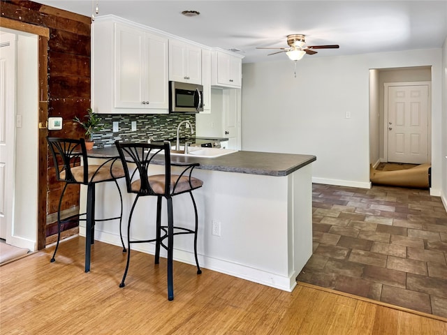 kitchen featuring ceiling fan, hardwood / wood-style flooring, decorative backsplash, and white cabinetry