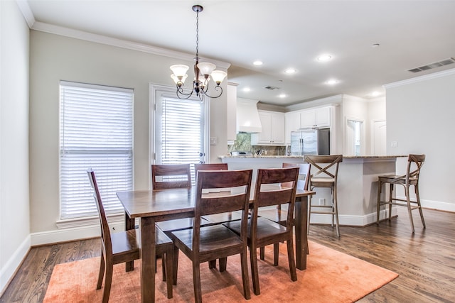 dining space with dark hardwood / wood-style floors, an inviting chandelier, and ornamental molding