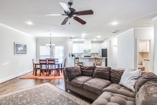 living room with ceiling fan with notable chandelier, ornamental molding, and hardwood / wood-style floors