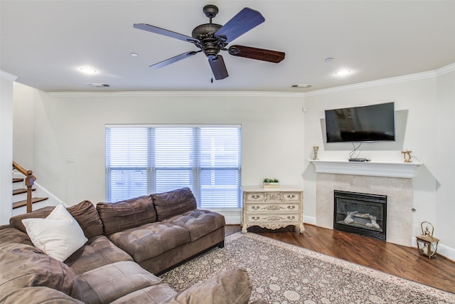 living room featuring hardwood / wood-style floors, ceiling fan, a fireplace, and crown molding