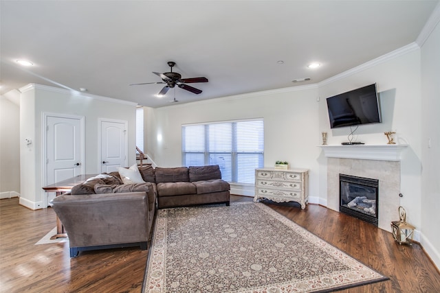 living room with crown molding, ceiling fan, a tiled fireplace, and dark hardwood / wood-style flooring