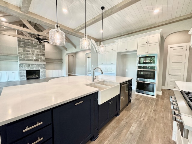 kitchen featuring white cabinets, hanging light fixtures, a fireplace, and light hardwood / wood-style flooring