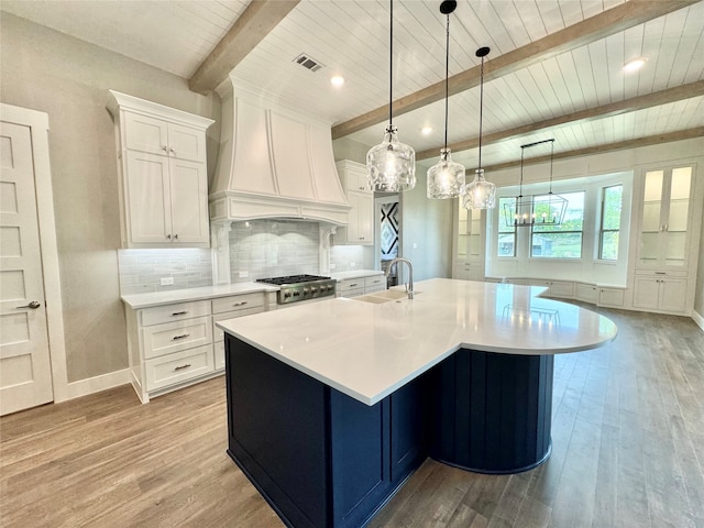 kitchen featuring white cabinetry, decorative light fixtures, beam ceiling, and light hardwood / wood-style floors