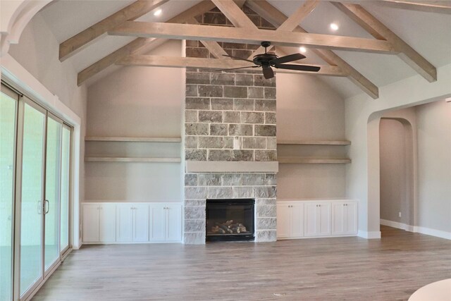 unfurnished living room with a fireplace, light wood-type flooring, beamed ceiling, and ceiling fan