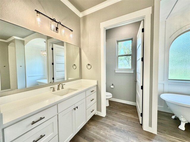 bathroom with toilet, crown molding, vanity, a bath, and hardwood / wood-style flooring