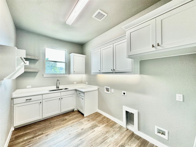 laundry area featuring hookup for a washing machine, hookup for an electric dryer, light hardwood / wood-style floors, sink, and cabinets