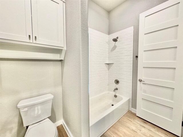 bathroom with wood-type flooring, toilet, and tiled shower / bath combo