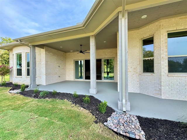 entrance to property featuring a lawn, ceiling fan, and a patio area