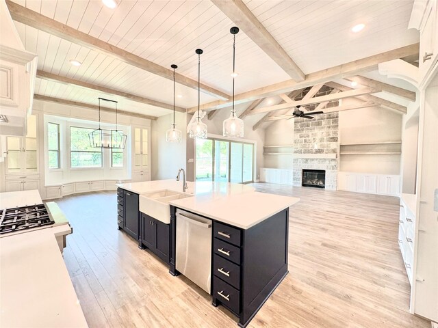 kitchen with plenty of natural light, an island with sink, vaulted ceiling with beams, and hanging light fixtures