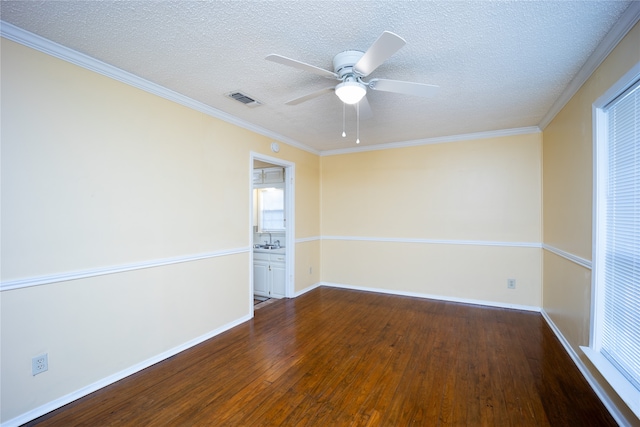 empty room featuring ornamental molding, dark hardwood / wood-style flooring, ceiling fan, and a textured ceiling