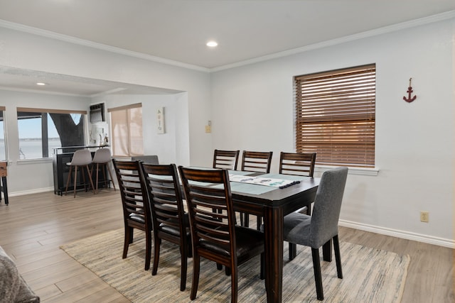 dining area with a water view, light hardwood / wood-style floors, and crown molding