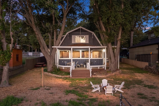 rear view of property featuring a sunroom and a fire pit