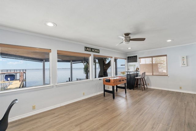 office featuring ceiling fan, light hardwood / wood-style floors, a water view, and a healthy amount of sunlight