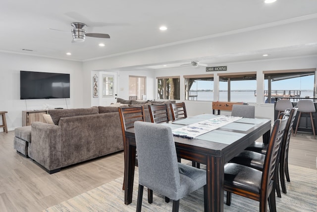 dining room with ceiling fan, light hardwood / wood-style flooring, and a water view