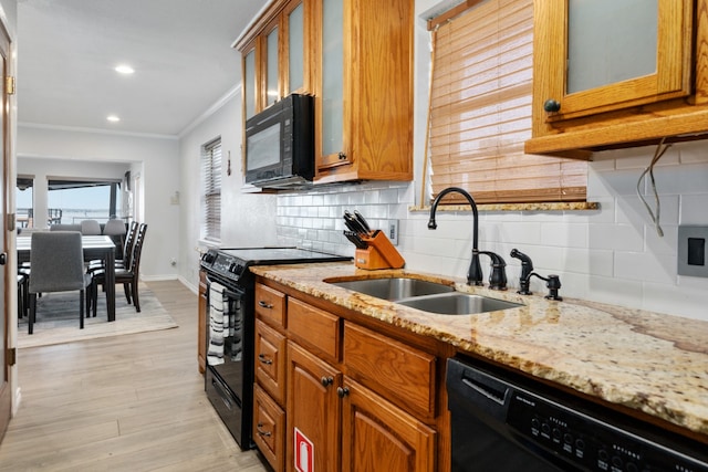 kitchen with light stone counters, light hardwood / wood-style floors, black appliances, backsplash, and ornamental molding