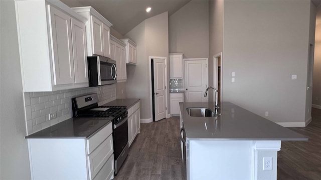 kitchen with sink, appliances with stainless steel finishes, a kitchen island with sink, white cabinets, and dark hardwood / wood-style flooring