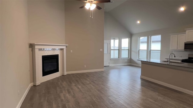 unfurnished living room featuring ceiling fan, high vaulted ceiling, sink, and dark hardwood / wood-style flooring