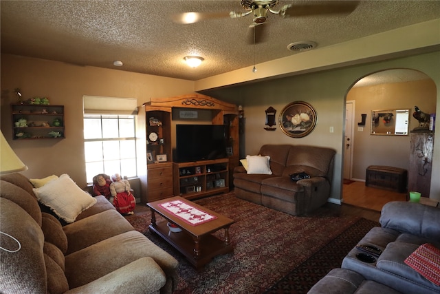 living room with a textured ceiling, wood-type flooring, and ceiling fan