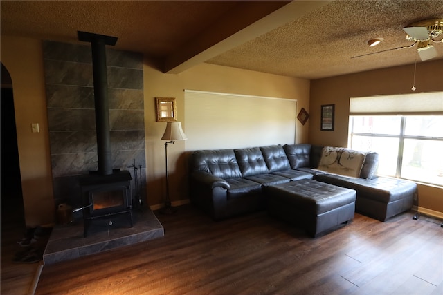 living room featuring a wood stove, ceiling fan, hardwood / wood-style flooring, and a textured ceiling