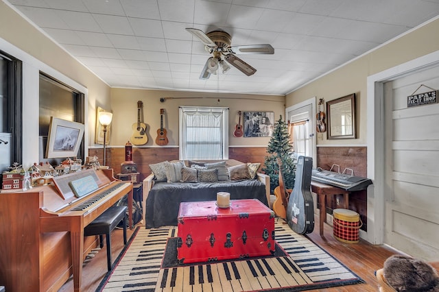 living room with wood walls, hardwood / wood-style floors, and ceiling fan