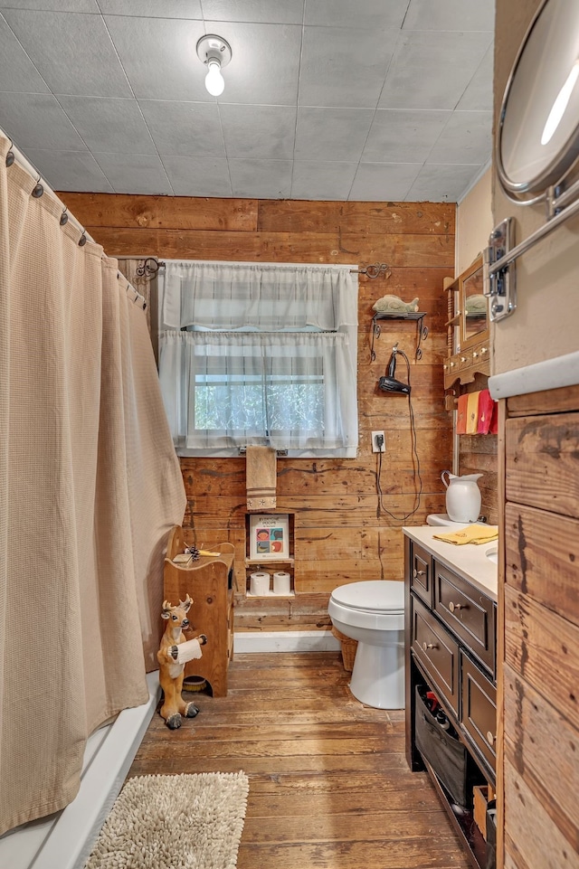 bathroom featuring vanity, toilet, wooden walls, walk in shower, and hardwood / wood-style floors