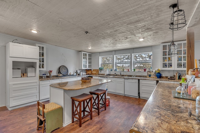 kitchen with pendant lighting, dishwasher, a center island, dark wood-type flooring, and white cabinets