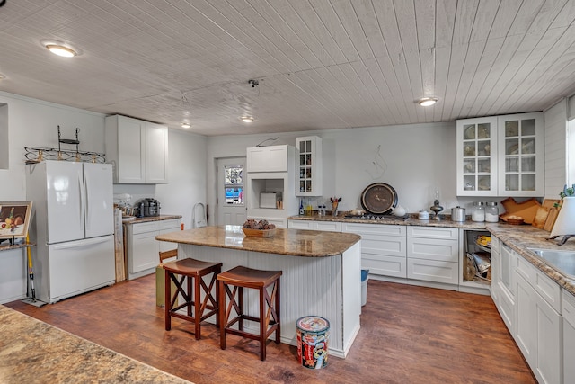 kitchen featuring white refrigerator, a center island, hanging light fixtures, and white cabinetry