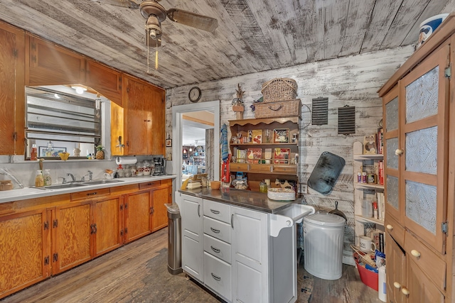 kitchen with light wood-type flooring, wood walls, sink, and ceiling fan